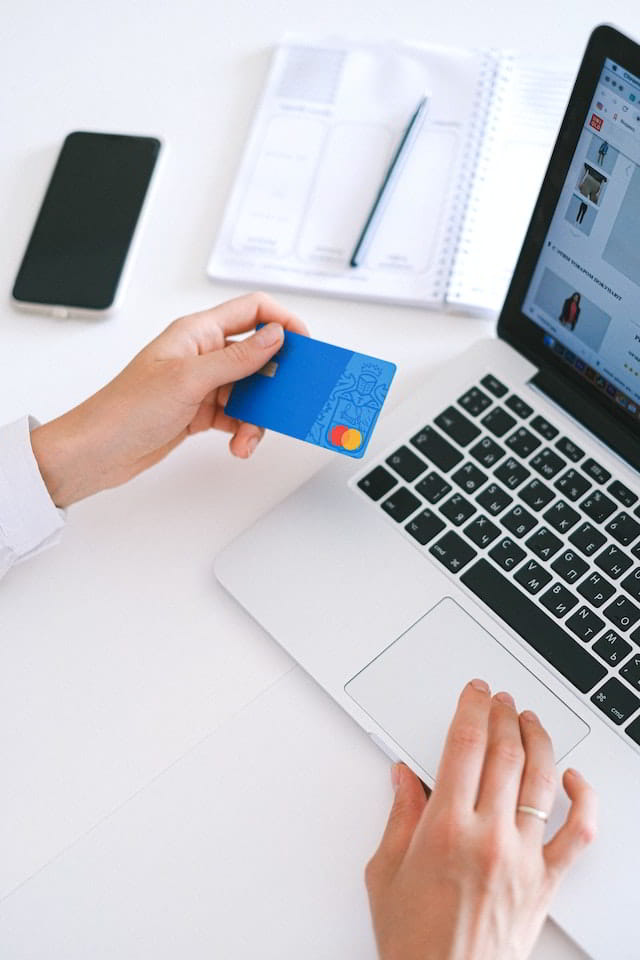 A person holding a credit card trying to make an online purchase through a laptop