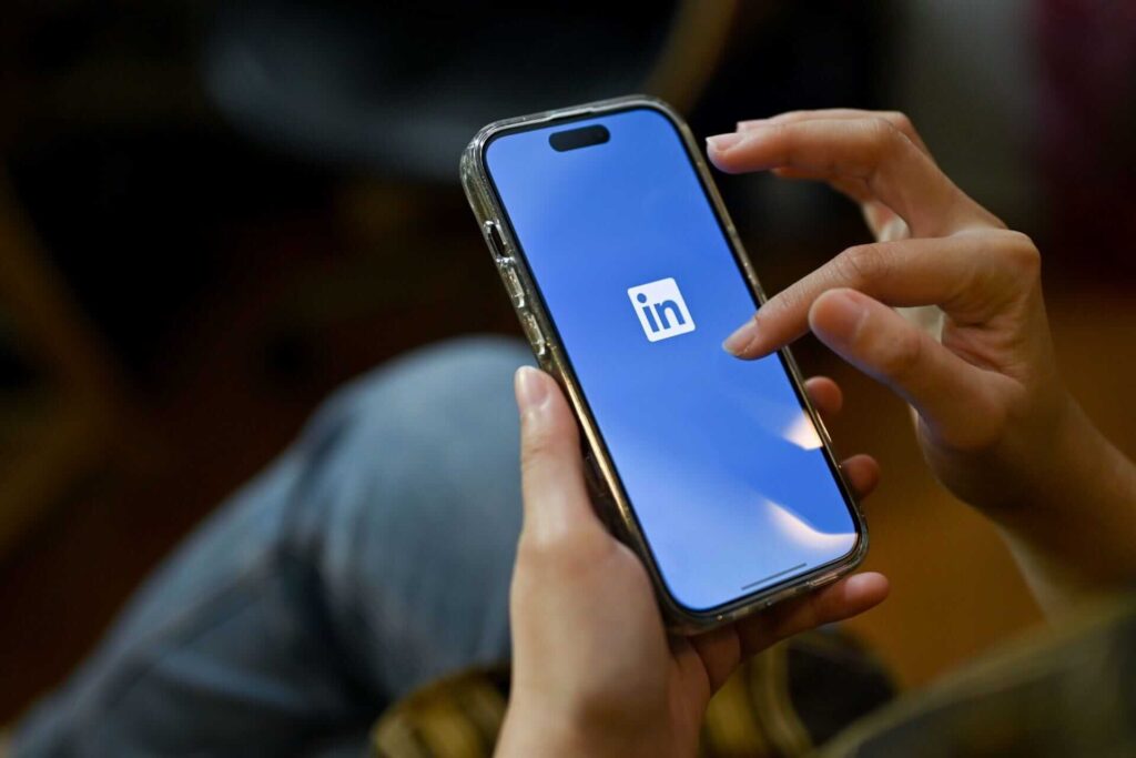 A lady holding a smartphone in her hand trying to open the LinkedIn app