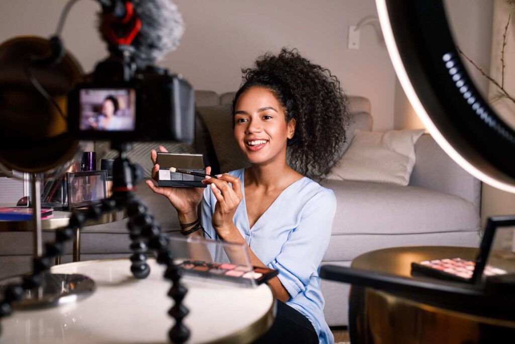 Smiling woman holding makeup palette while recording video for her blog